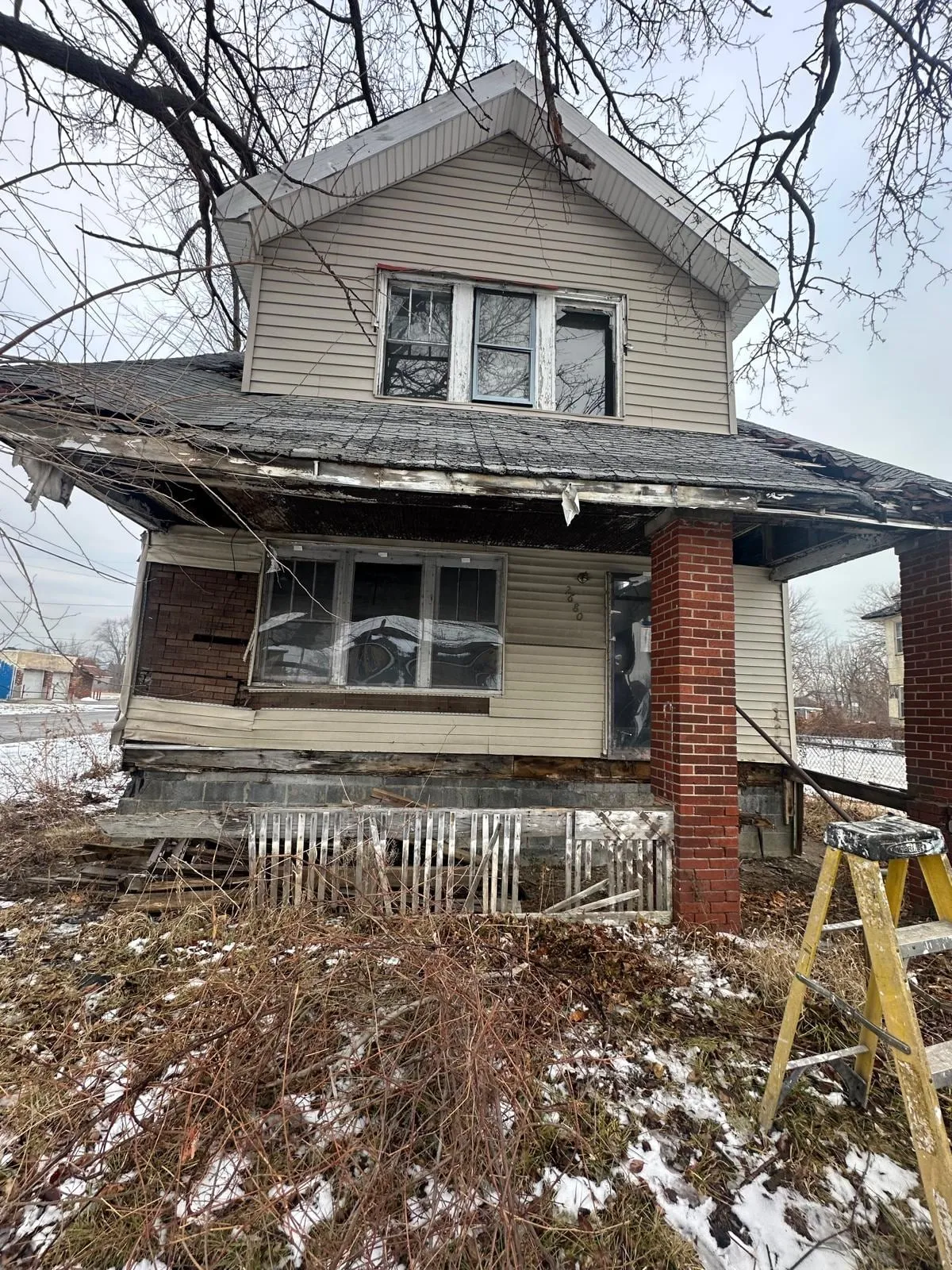 Fachada de la casa de Lakewood antes de la rehabilitación: porche vencido, ventanas tapiadas y revestimiento desprendido